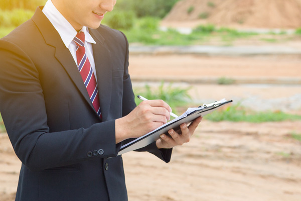 Man in suit writing on a clipboard