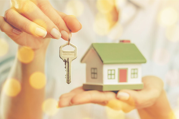 Woman holding house keys and model of home in her hand