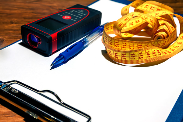 Measuring device and tape measure laying on a clipboard